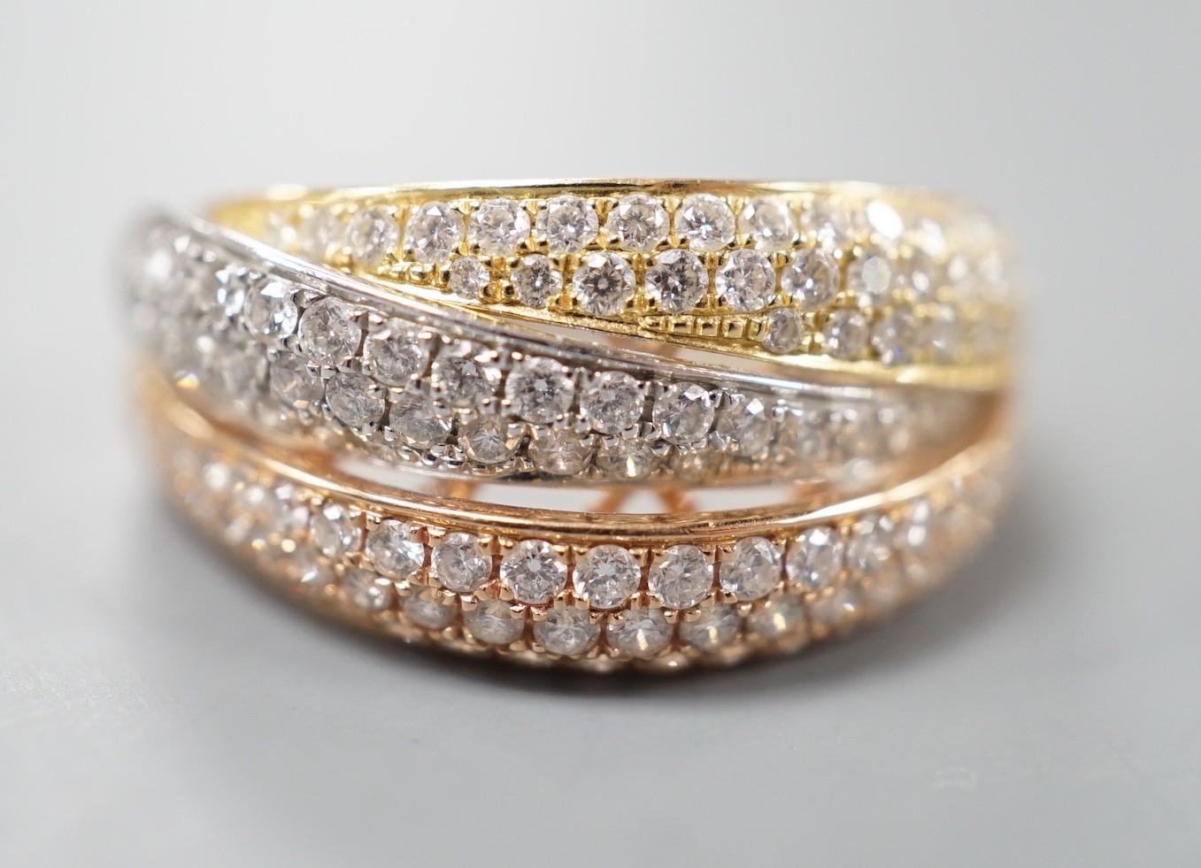 A modern three colour 18ct gold and diamond chip set triple band crossover ring, size O, gross weight 7 grams.